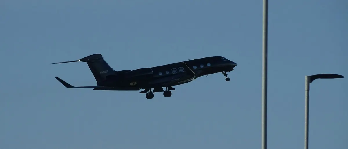 Business jet landing at dusk between runway light poles