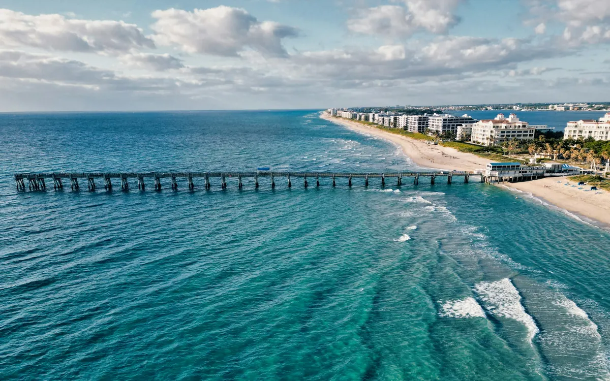 Aerial view of a long pier and beach in Palm Beach County